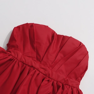 Detail of red strapless top featuring pleated fabric and structured waist design