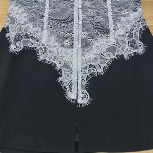 Close-up of elegant black blazer with white lace splicing and refined decorative buttons