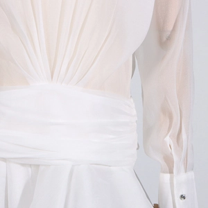 Detail of white mesh dress showing ruched waist design and sheer sleeves with button