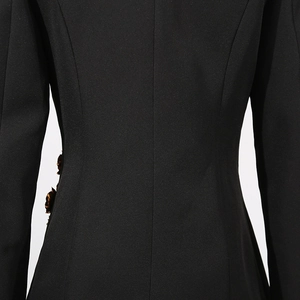 Detail of the back waist stitching and 3D floral accent on a black tailored blazer