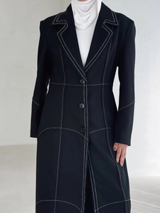 Elegant black long trench coat with white contrast stitching and waist-shaping design