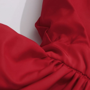 Detailed close-up of red ruffled fabric with fine plain weave and gathered pleats