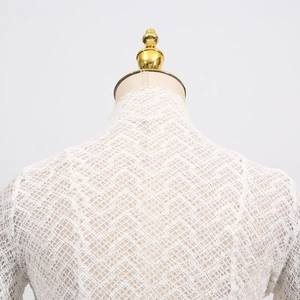 Detail of white knit lace high neck top showing intricate woven texture on a mannequin