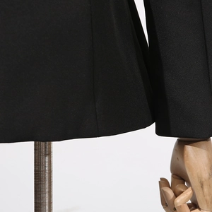 Detailed close-up of fine-textured black blazer fabric and precise stitching quality