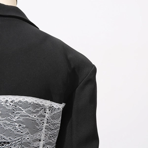 Detail view of the intricate white lace splicing design on the back of the black blazer