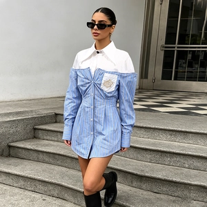Dettaglio di un abito a camicia a righe blu e bianche con ricami e maniche lunghe