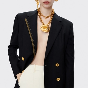 Detail eines schwarzen zweireihigen Blazers mit goldener Linealstickerei und Lippenkette