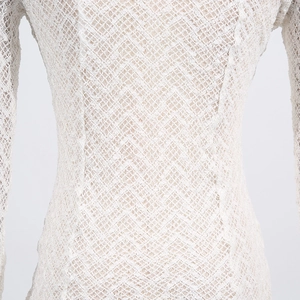 Close-up of cream white knit shirt showing delicate wavy lace texture and hollow design
