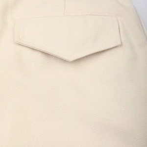 Detail view of beige trousers showing twill fabric texture and stitched pocket flap