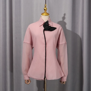 Detailed view of pink blouse with 3D black flower decoration and sheer puff sleeves