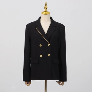 Detail des dekonstruierten Revers mit goldenem Metallbesatz am schwarzen Slim-Fit Blazer
