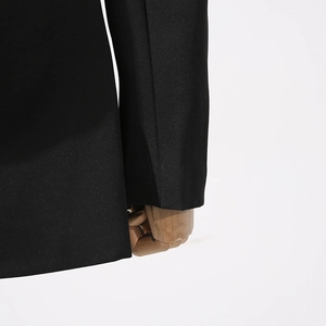 Detail of black lace-paneled blazer sleeve with sharp tailoring and premium woven texture