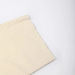 Detailed view of cream white twill fabric texture and raw edge craftsmanship on trousers