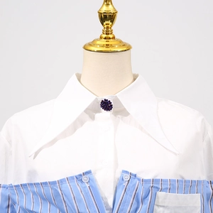 Dettaglio di una camicia bianca con righe blu, colletto a punta e perla viola
