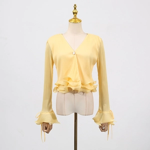Detail of light yellow pleated knit cardigan with ruffled cuffs and V-neckline button