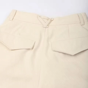 Detail of off-white corduroy pants featuring rear V-buckle and cargo flap pockets