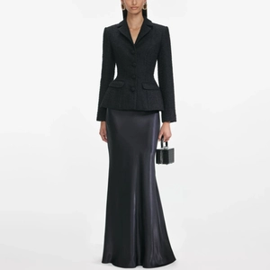 Dettagli di un completo con blazer peplum in tweed nero e gonna lunga in raso lucido