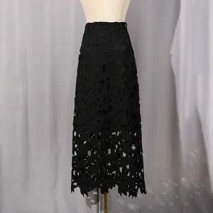 Détail d'une jupe midi en dentelle noire avec broderie florale ajourée et ourlet festonné