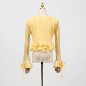 Detail of light yellow pleated knit cardigan featuring ruffle hem and ribbon bow sleeves