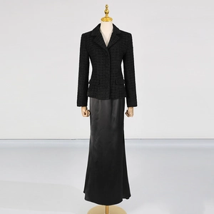 Dettaglio del set con blazer in tweed nero e gonna lunga in raso a vita alta