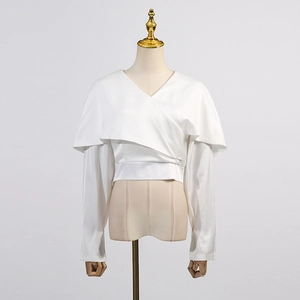 Détail d'un chemisier en satin blanc avec col châle superposé et décolleté en V