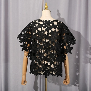 Détail du tissu en dentelle noire ajourée à motif floral et texture du vêtement