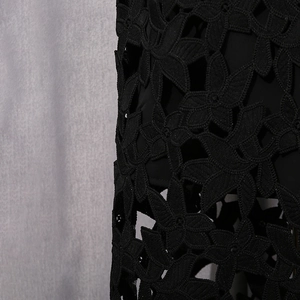 Détail du tissu en dentelle noire avec broderie florale et texture ajourée chic