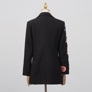 Détail de broderies florales 3D colorées sur la manche de la veste blazer noire