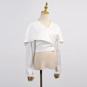 Détails de la texture satinée blanche et du col drapé sur cette chemise élégante