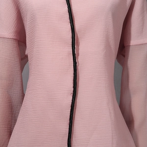 Detail of pink pleated blouse with black trim and sheer lantern sleeve texture
