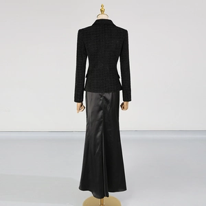 Dettaglio di blazer in tweed nero con gonna a sirena in raso su manichino, vista posteriore