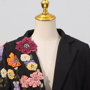Détail de broderies florales 3D avec perles et strass sur veste de blazer noire chic