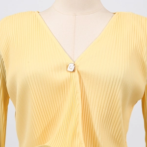 Close-up of yellow pleated knit cardigan featuring a V-neck and decorative square buckle