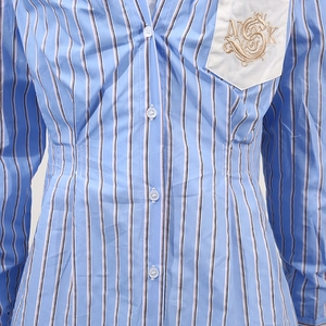 Dettaglio camicia a righe blu con taschino bianco sul petto e ricamo dorato