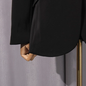 Detailaufnahme des geschwungenen Saums und der hochwertigen Nähte des schwarzen Blazers