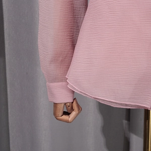 Detail of pink blouse showing textured crinkled fabric and lantern sleeve cuff design