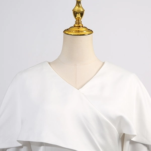 Détail d'un chemisier blanc en satin avec col en V croisé et volants élégants superposés