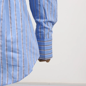 Dettaglio della manica di camicia a righe azzurre con trama del tessuto e cuciture fini