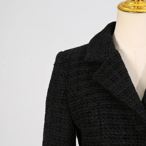 Dettaglio della giacca in tweed nero con colletto sofisticato e cuciture sulle spalle