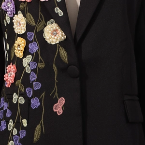 Gros plan de broderie florale 3D avec perles et strass sur un blazer noir