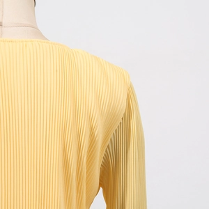Detailed macro view of yellow pleated fabric texture and ruffled neckline on the top