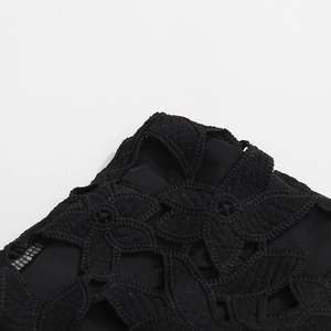 Détail macro de la broderie florale noire et de la texture dentelle de la jupe