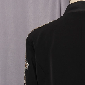 Detail eines schwarzen Blazers mit aufwendiger Strassverzierung an Schulter und Ärmel für Damen