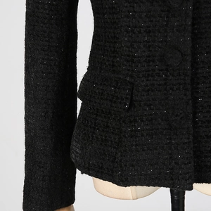 Dettaglio ravvicinato del tessuto tweed nero con glitter argento e patta della tasca