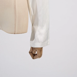 Détail des poignets d'une chemise en satin blanc avec bouton et coutures fines