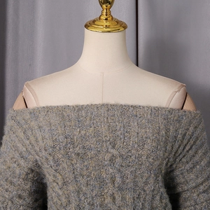 Close-up of gray cable knit sweater dress featuring an off-the-shoulder design and texture