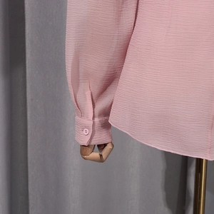 Detailed close-up of pink lantern sleeve cuff with button and pleated fabric texture