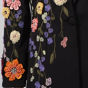 Détail de broderie florale 3D avec perles et strass sur une veste blazer noire
