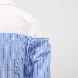 Dettaglio delle cuciture a contrasto su una camicia a maniche lunghe a righe da donna