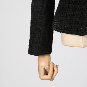 Dettaglio del tessuto in tweed nero della giacca da completo con trama ricca e brillante